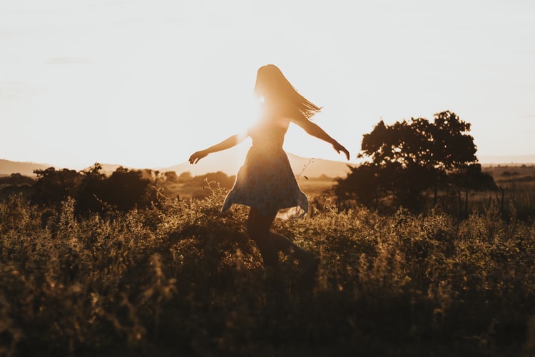 A woman walking in front of the sun