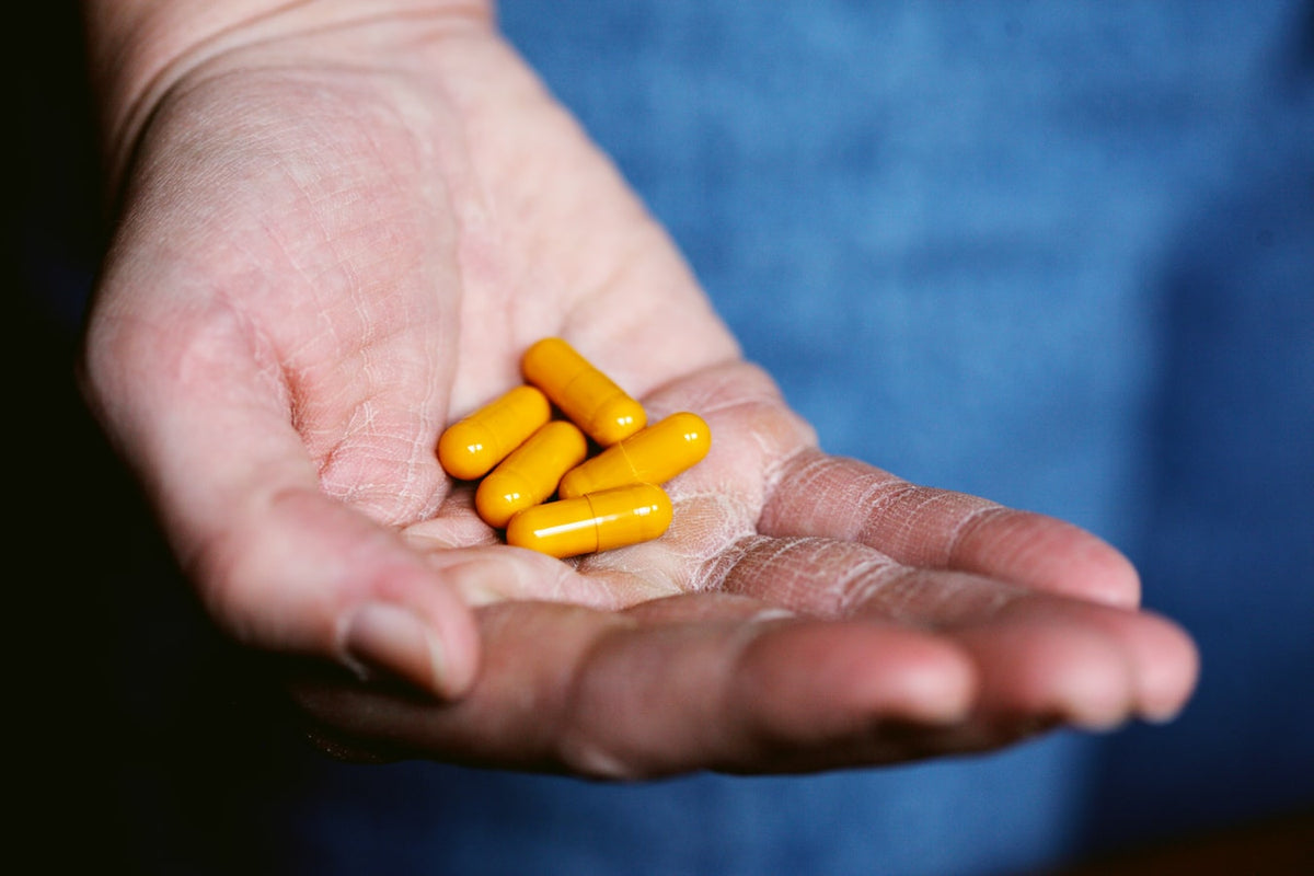 A persons hand holding orange pills