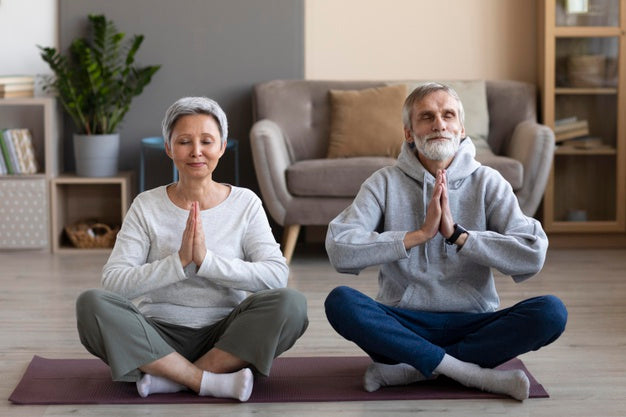 An elderly couple meditating on a yoga mat