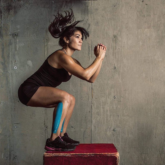 A woman jumping on a box with kinesiology tape on her calfs