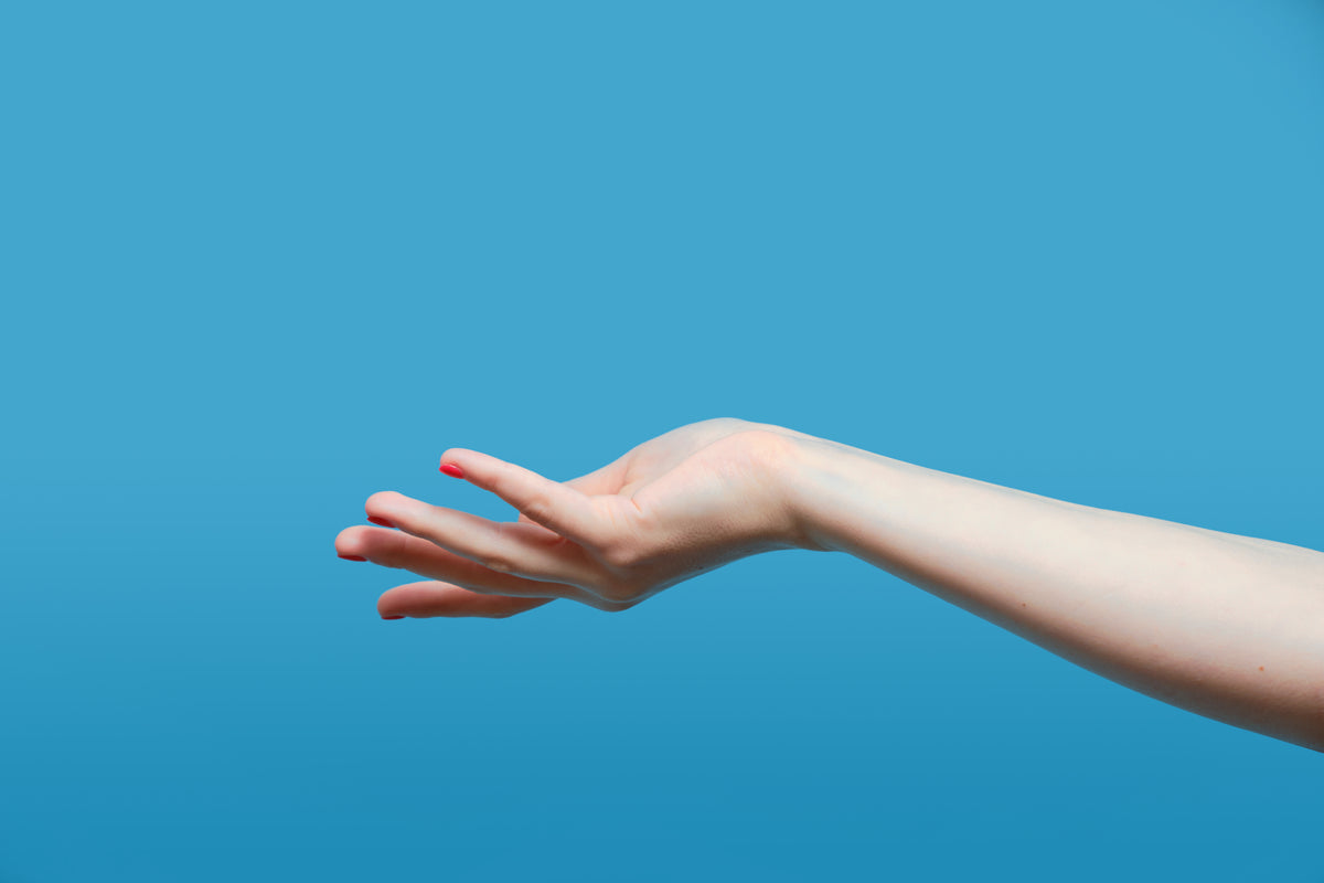 A person’s hand reaching over a blue background