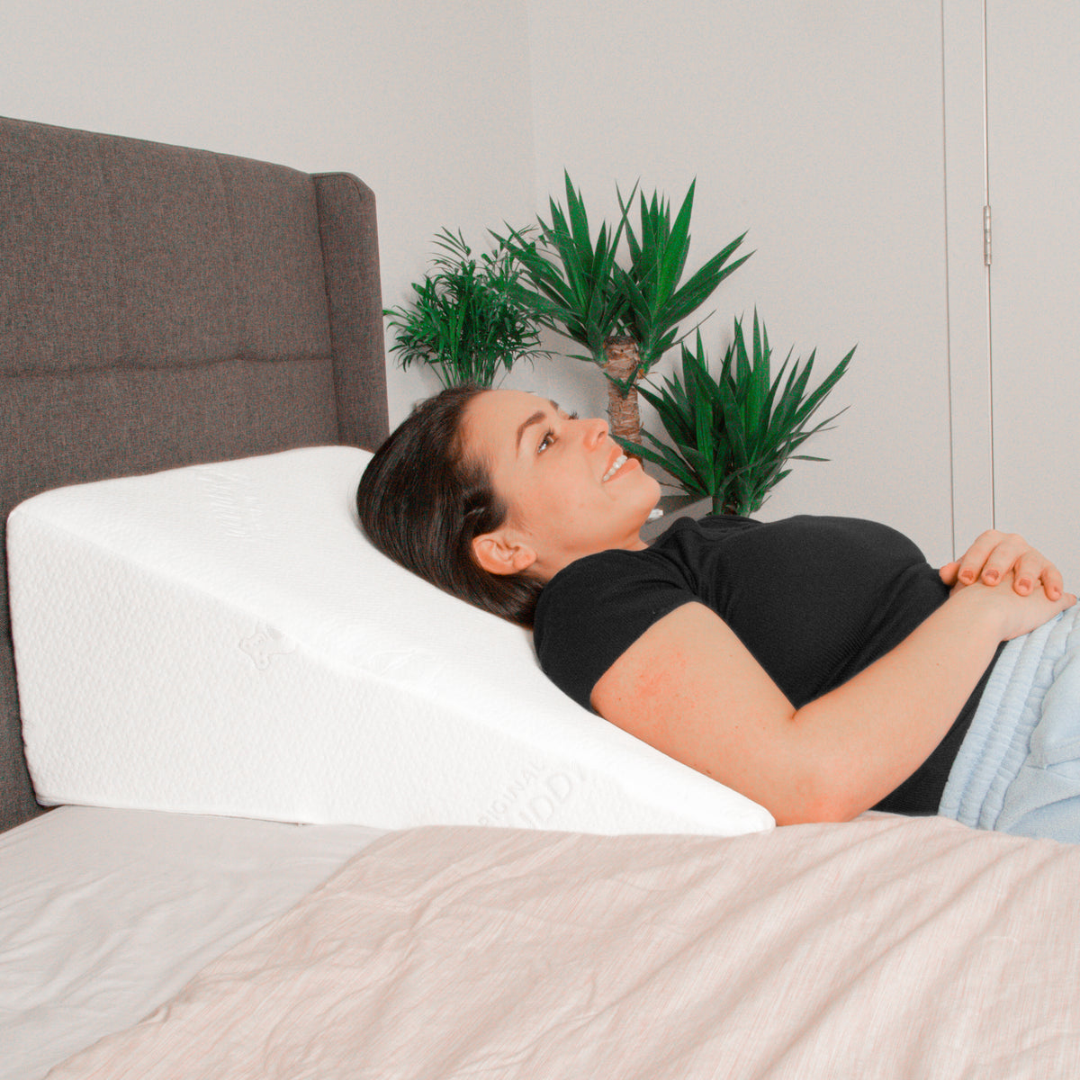 A woman laying on her back in bed on a wedge pillow
