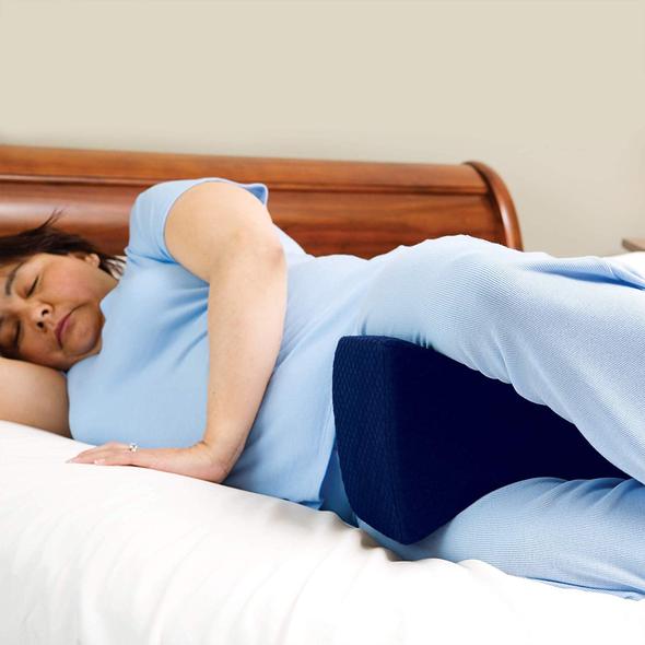 A woman sleeping in bed with a knee pillow