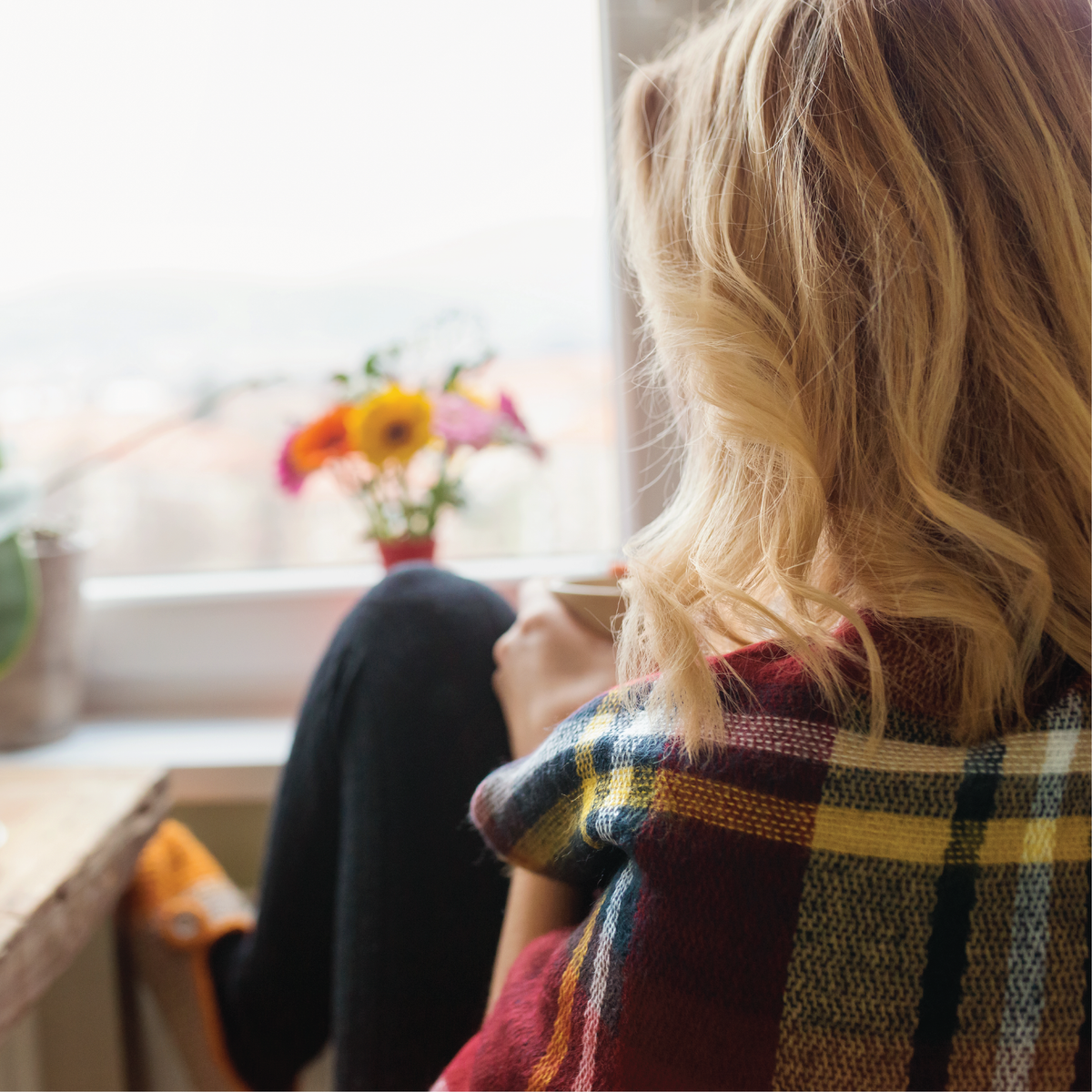 A woman sitting in a chair looking out a window