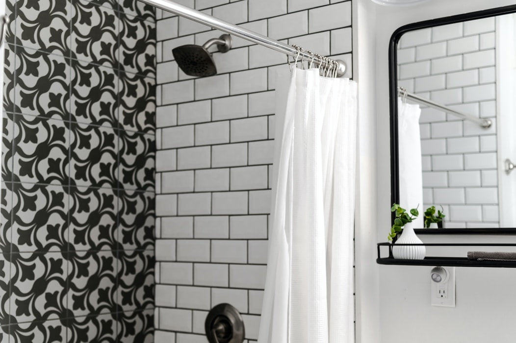 A bathtub with a white and black tiled wall