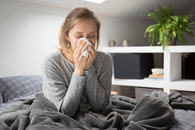 A woman blowing her nose from being sick