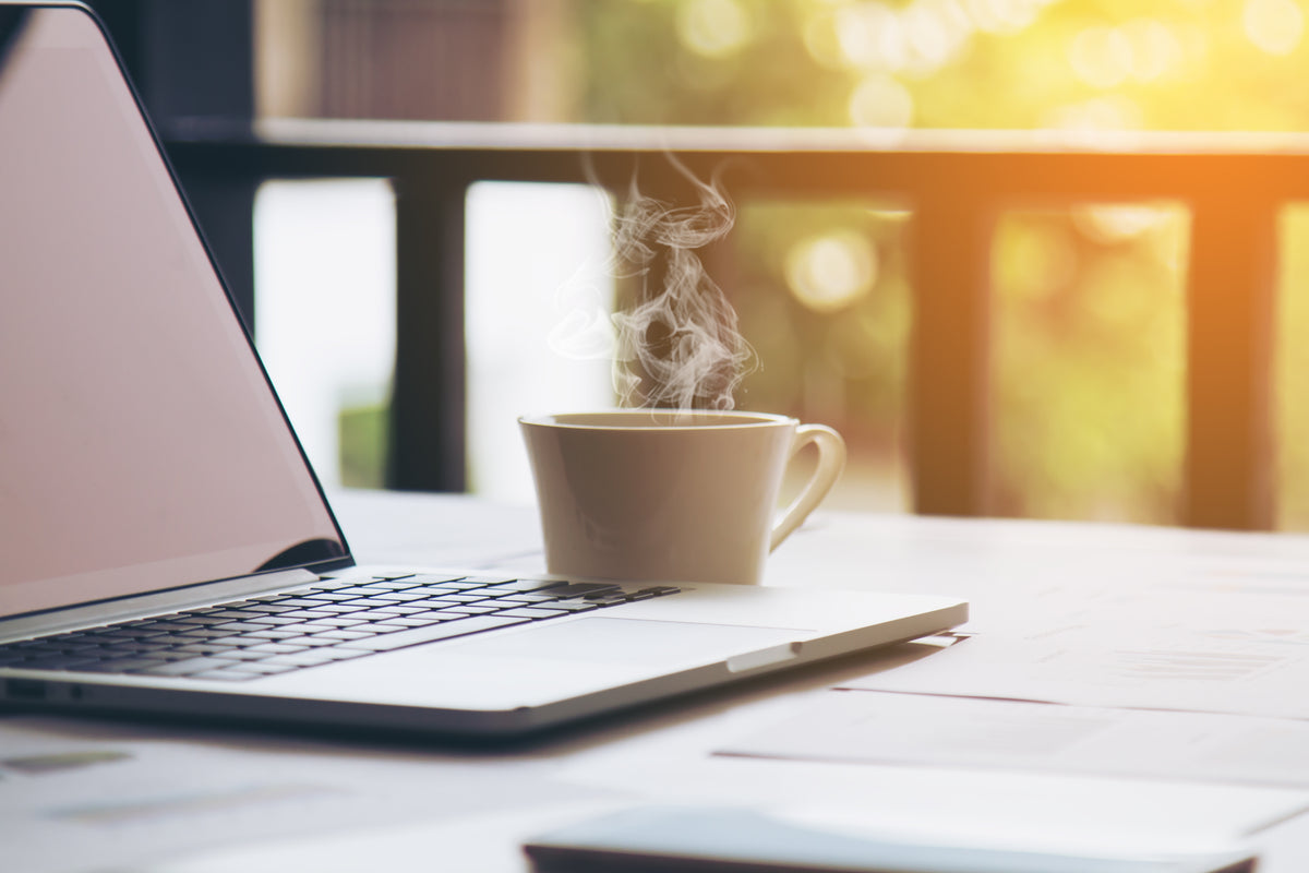 A cup of coffee on a table in front of sunlight