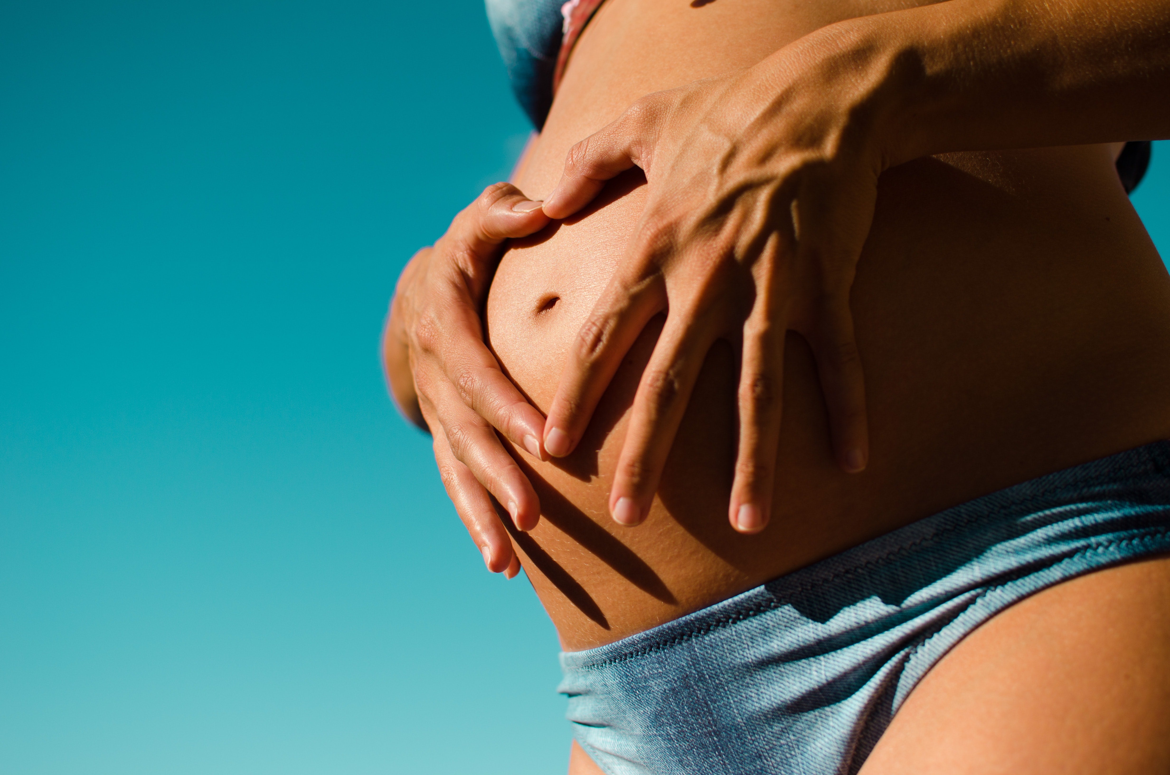 A woman with her partner hands over her pregnant stomach