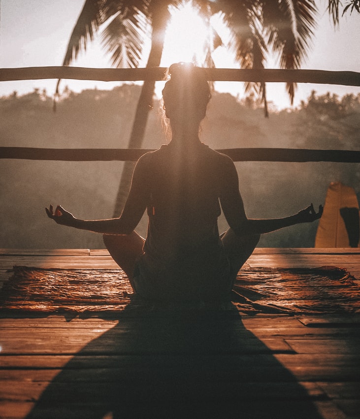A woman meditating in front of the sun