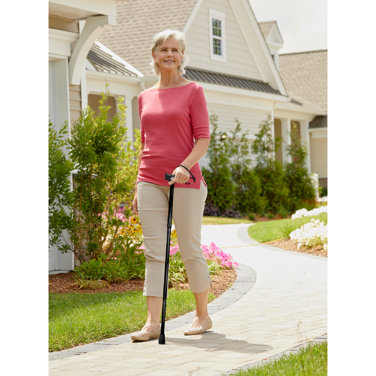 A woman walking outside in a neighbourhood with the Carex walking cane