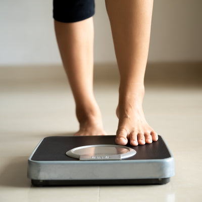 A close up of a person stepping on a weight scale