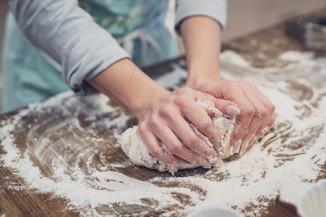 A woman holding dough on a cutting board