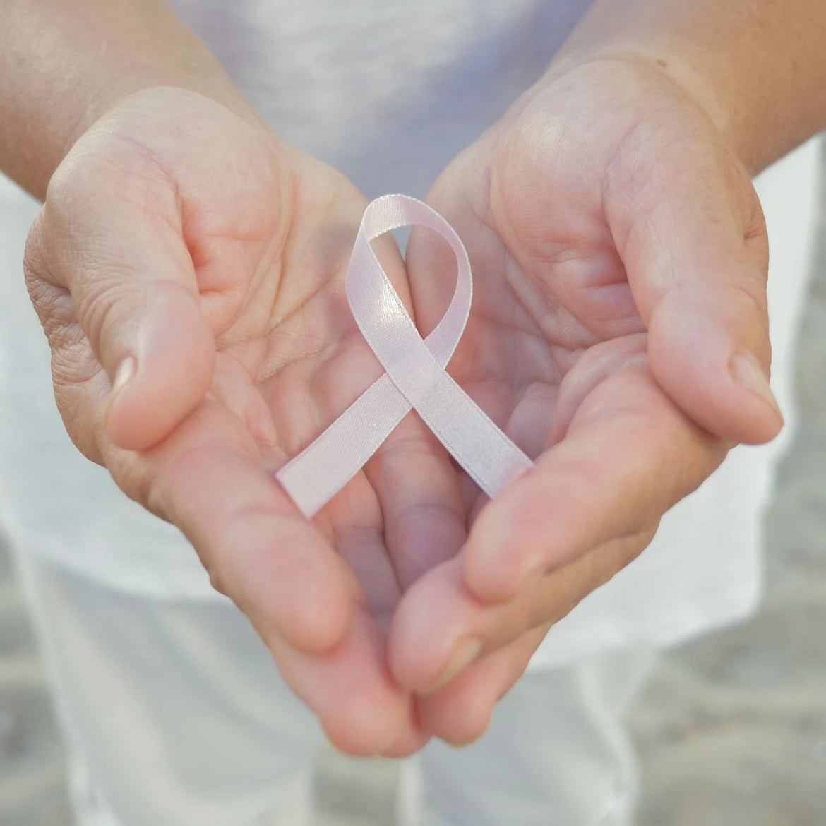 Hands holding a cancer ribbon