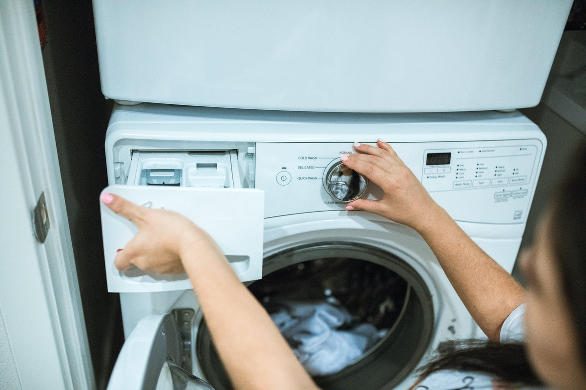 A woman turning on a washing machine