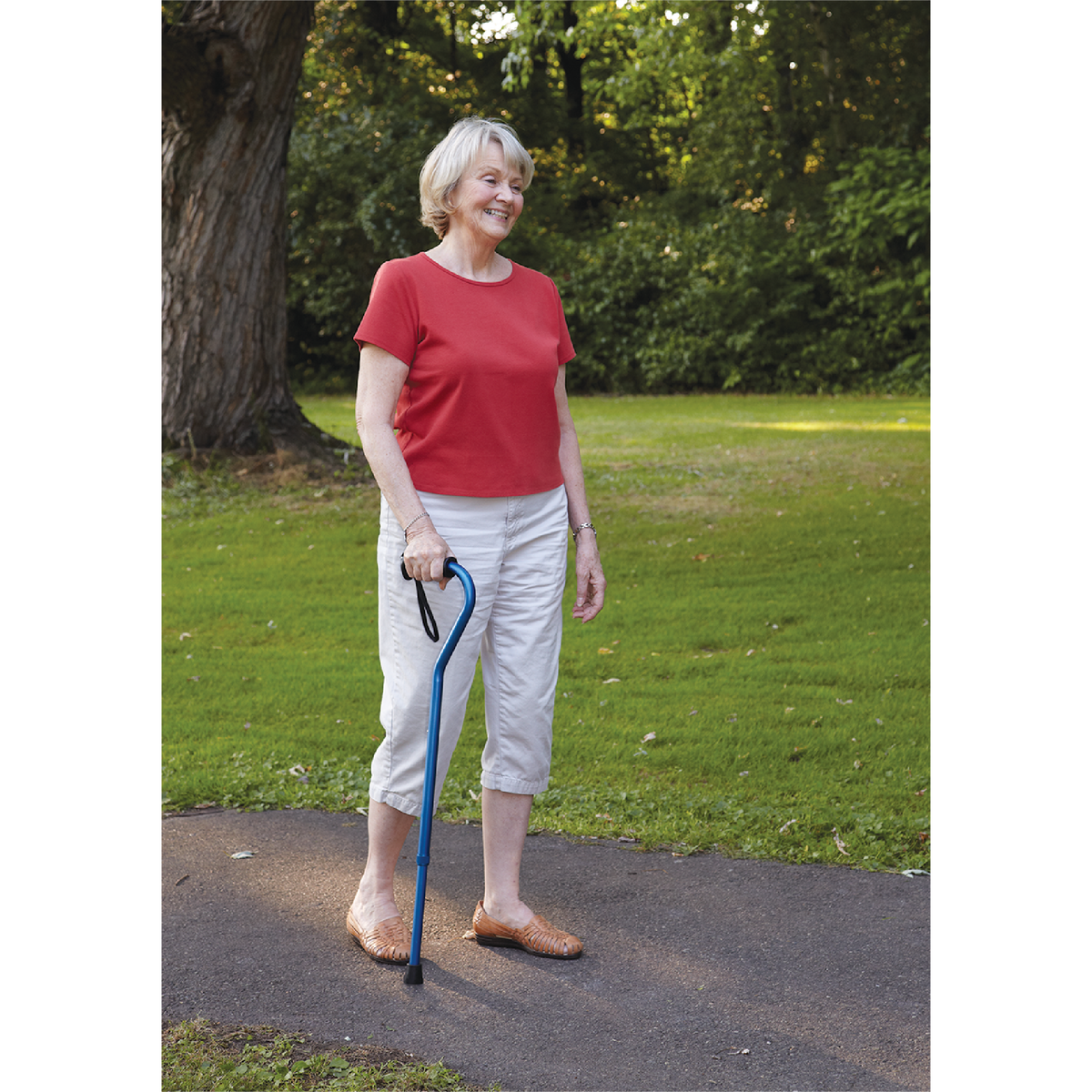 An elderly woman outside walking with the Carex Ergo Offset Walking Cane