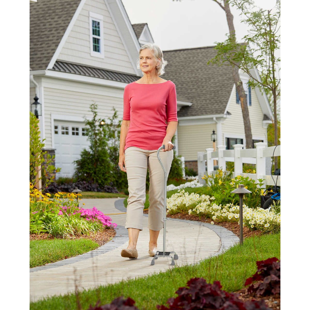 A woman walking outside in a neighbourhood with the Carex Small Base Offset Quad Cane