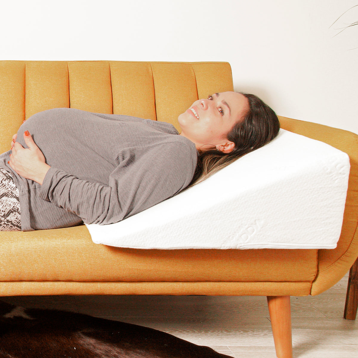 A woman laying on a wedge pillow on a couch