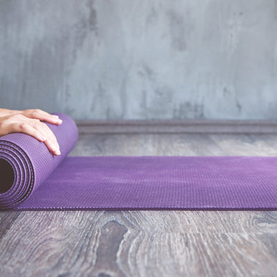 Close up of a purple yoga mat being rolled up