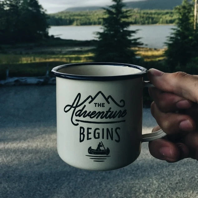 A coffee mug that reads “the adventure begins here”