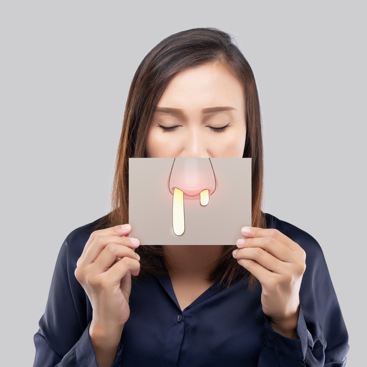 A woman holding ap picture of a running nose to her face