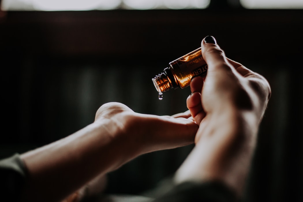 A person dropping an essential oil onto their hand