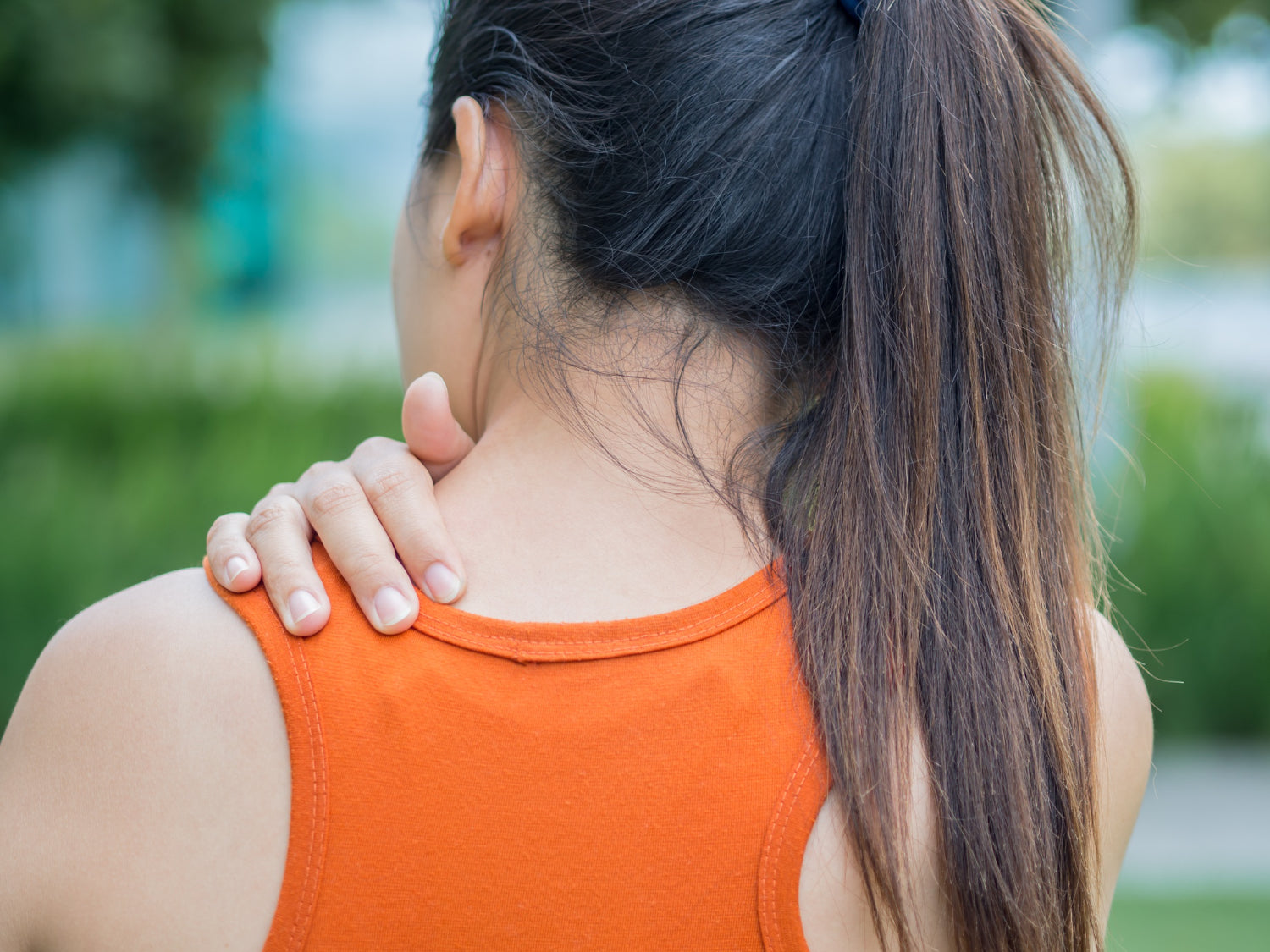A woman holding her upper back in pain