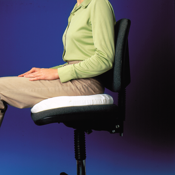 The Carex Foam Invalid Cushion with a person sitting on it on a chair