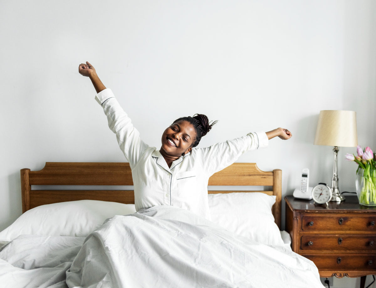 A woman stretching her arms waking up in bed