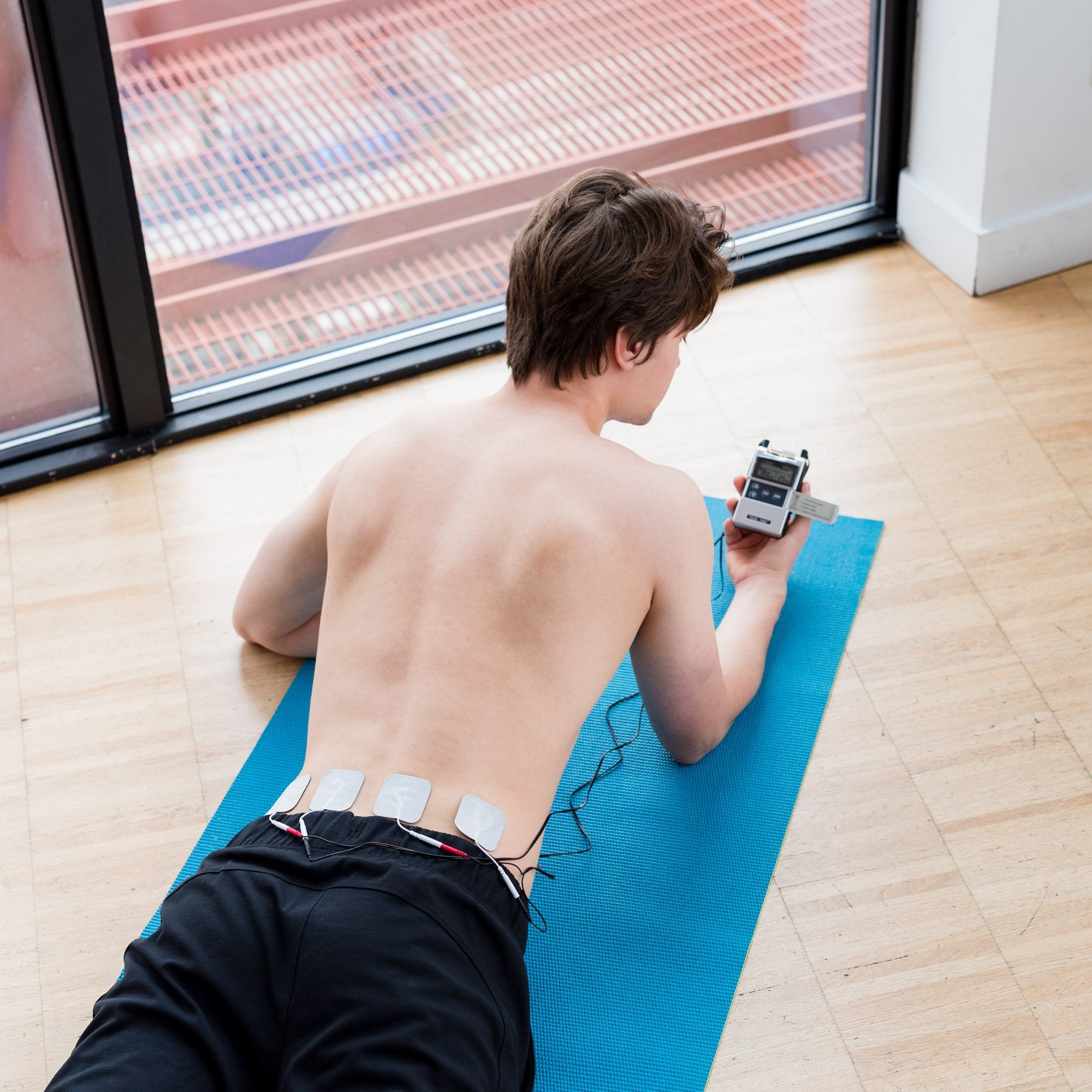 A man using a tens unit on his SI joint