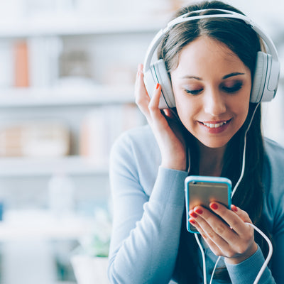 A girl with headphones on looking at her phone