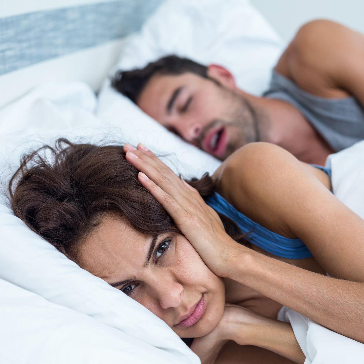 A woman upset as her man snores in bed
