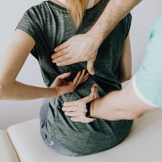 A close up of a physical therapist adjusting a patient’s back