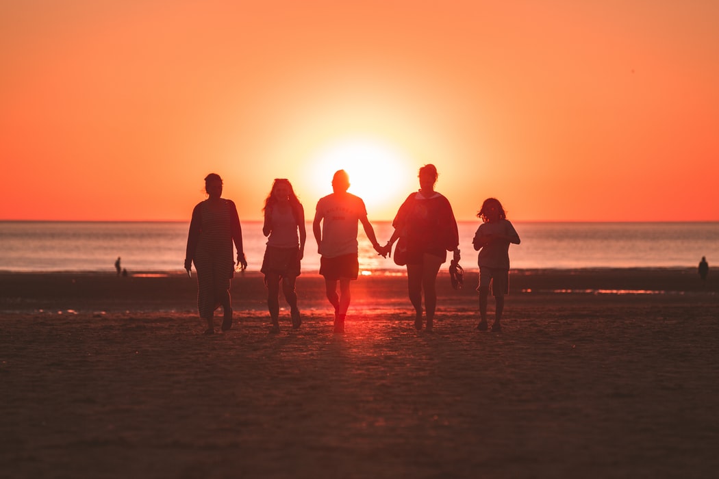 A family walking on a beach at sunset