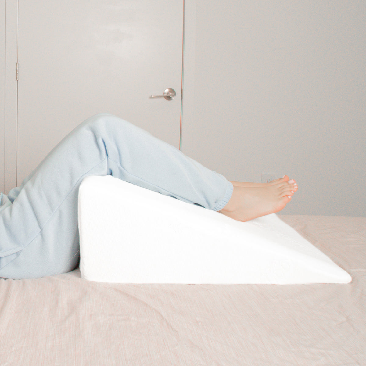 A wedge pillow on a bed with legs on it