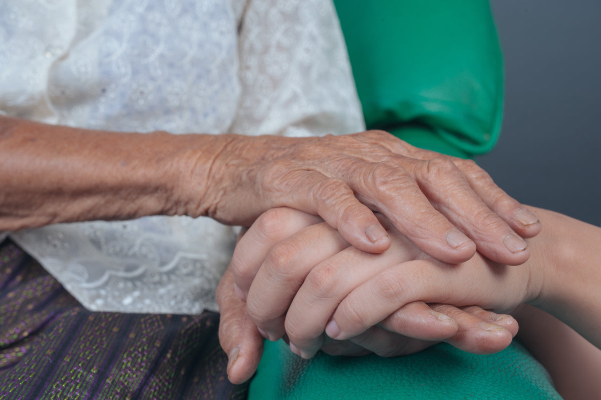 An elderly womans hand holding another hand