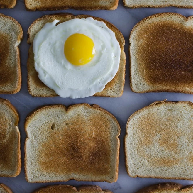 Toast lined up with an egg on top of one