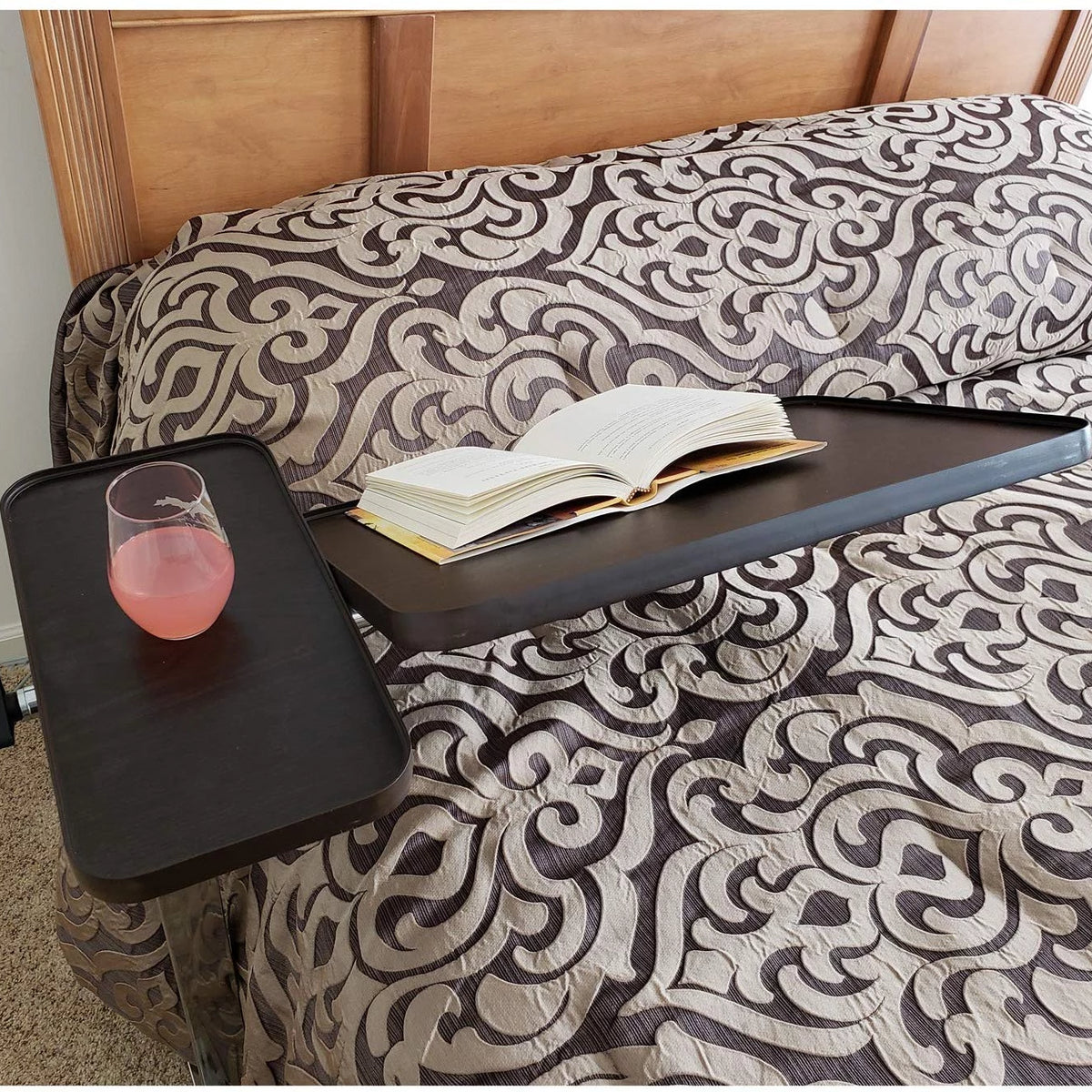 An overbed table over a bed with a book and drink on it