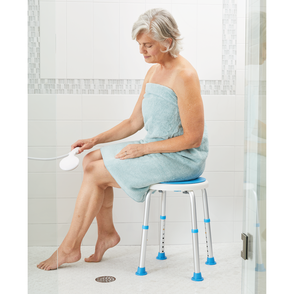 An elderly woman using a shower stool in a shower