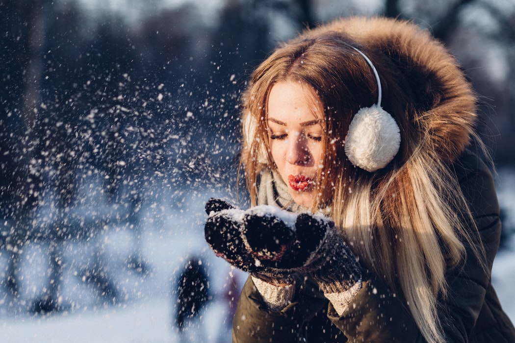 A woman blowing snow from her hands