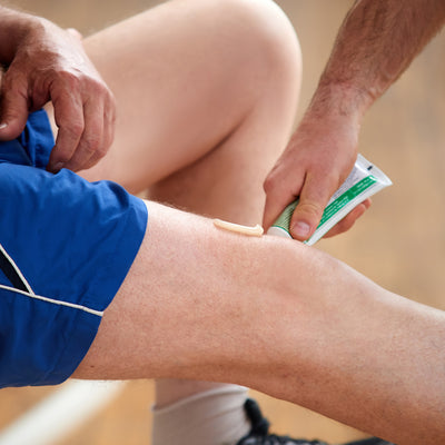 Close up of pain relief gel being applied to a person’s knee