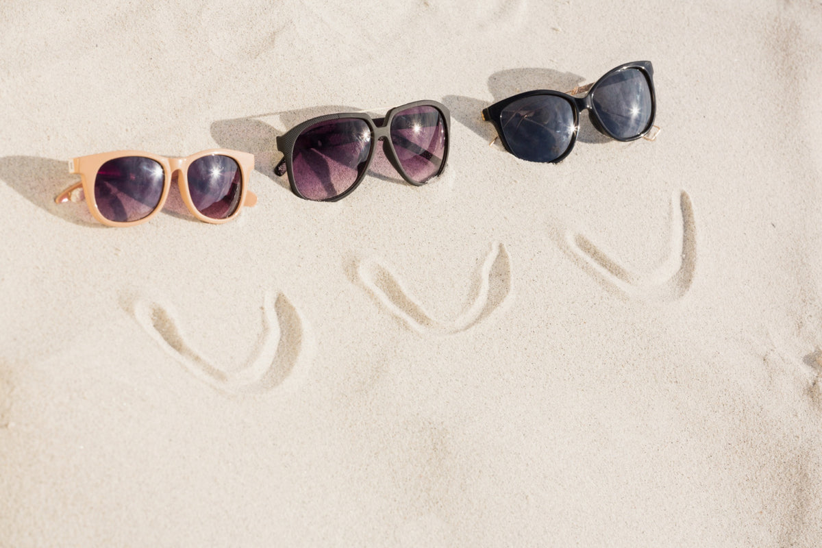 Three pairs of sunglasses on sand