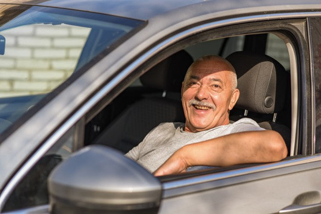 A senior man sitting in his car smiling