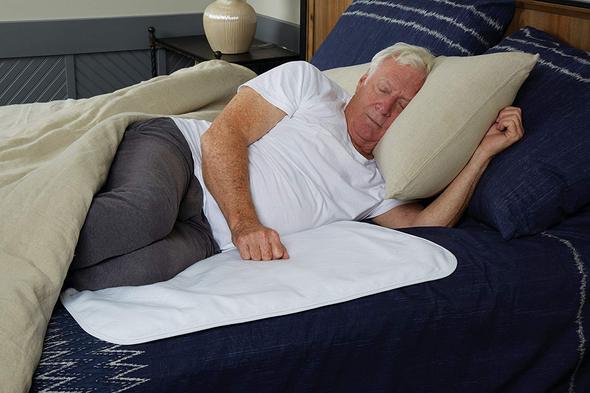 A man sleeping on his side on top of an incontinence pad