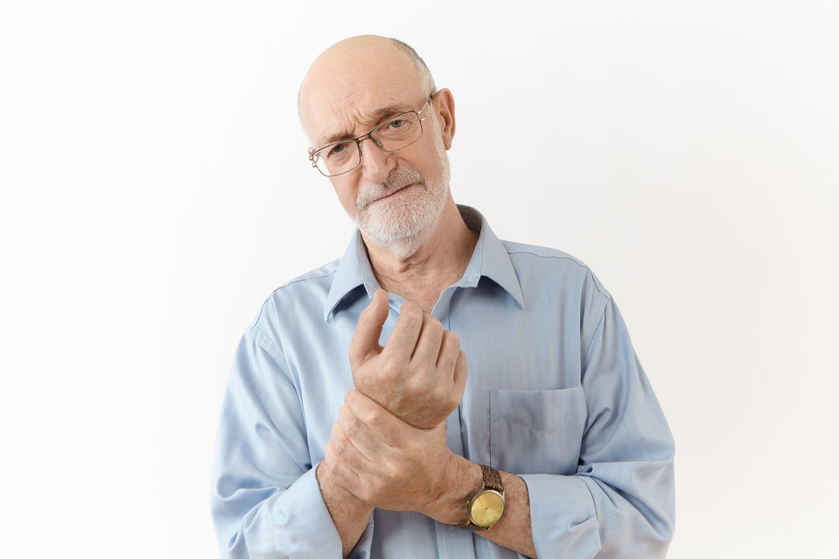 An elderly man holding his wrist in pain
