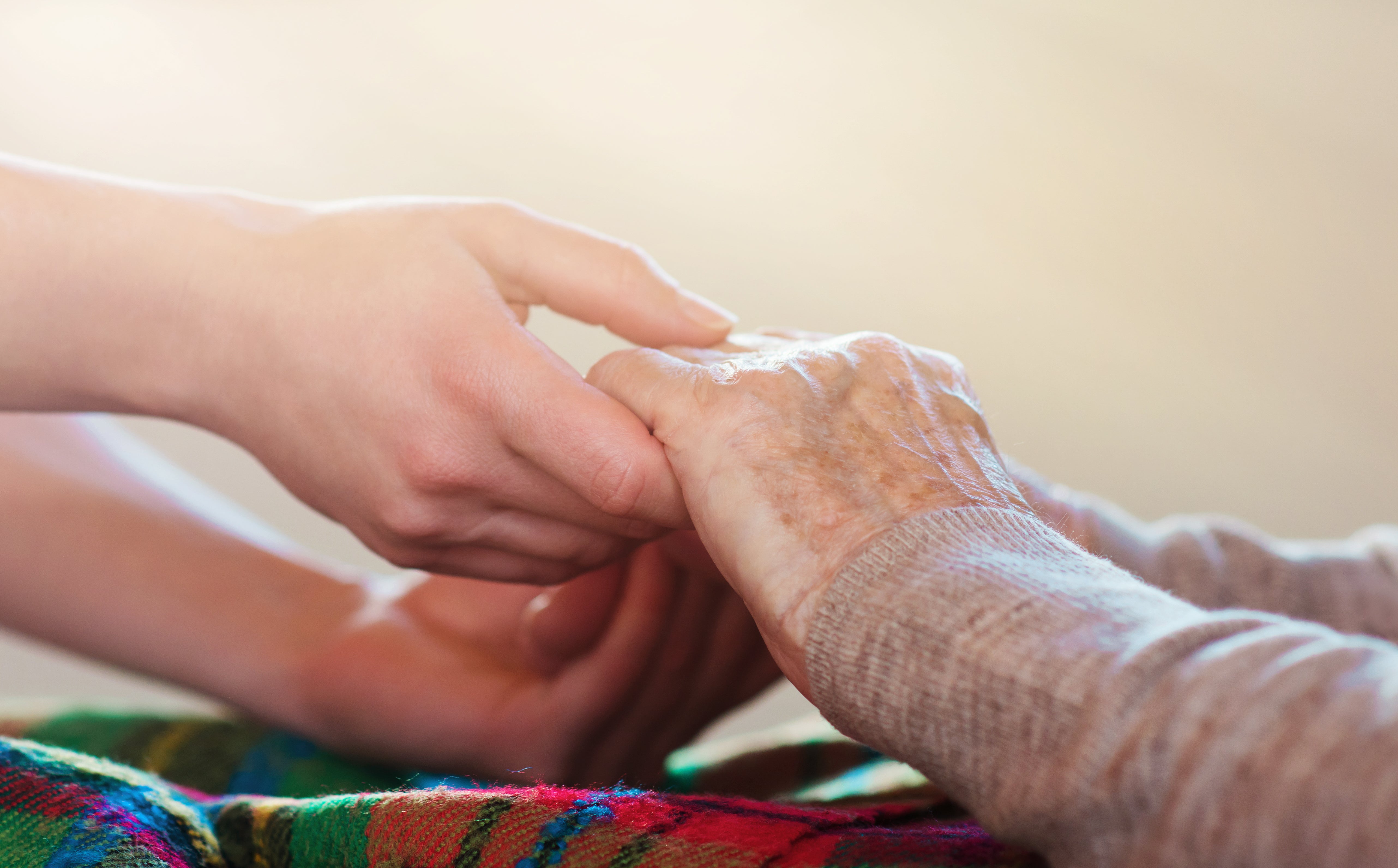 A younger woman's hands holding a seniors hands
