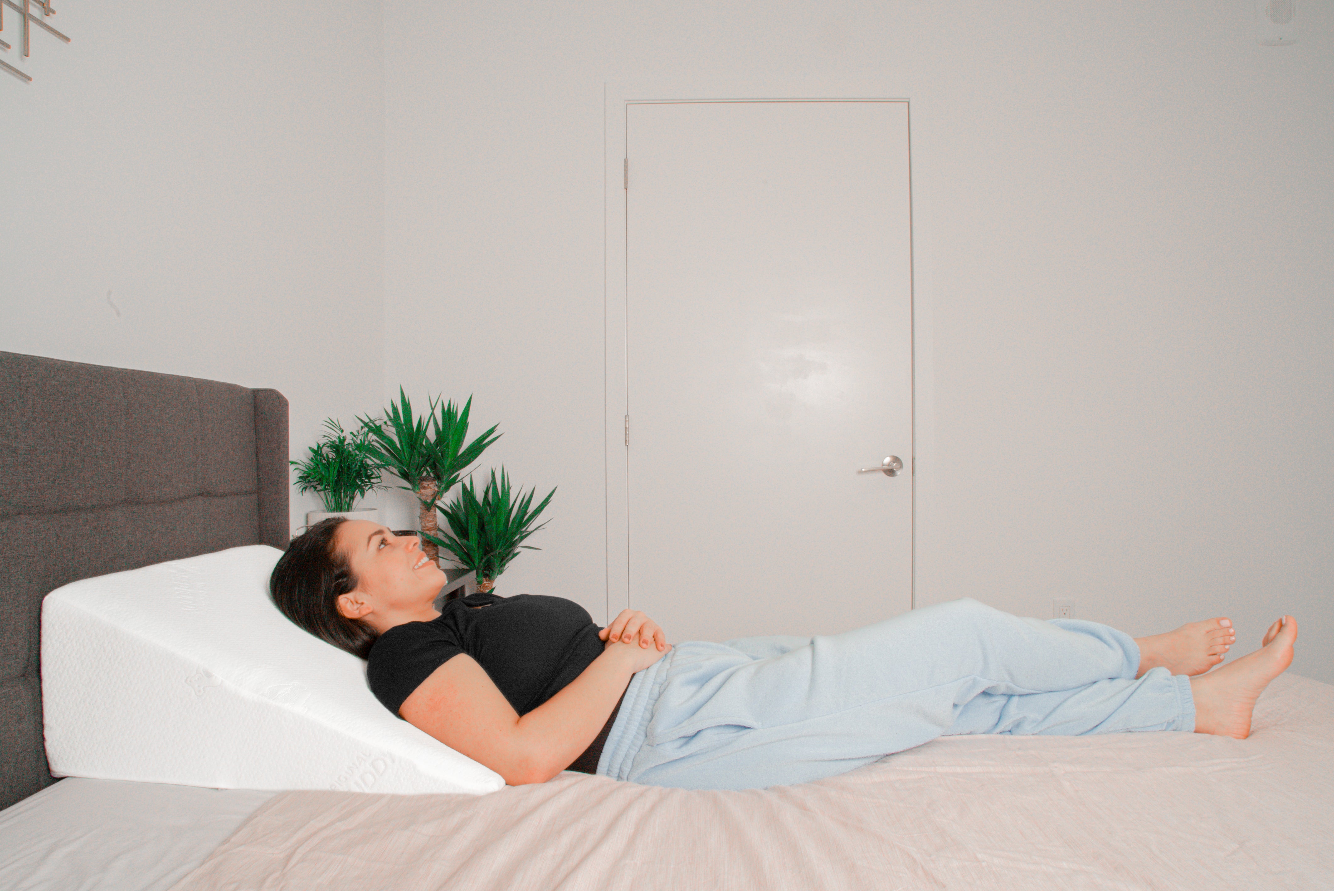 A woman laying on a wedge pillow in bed