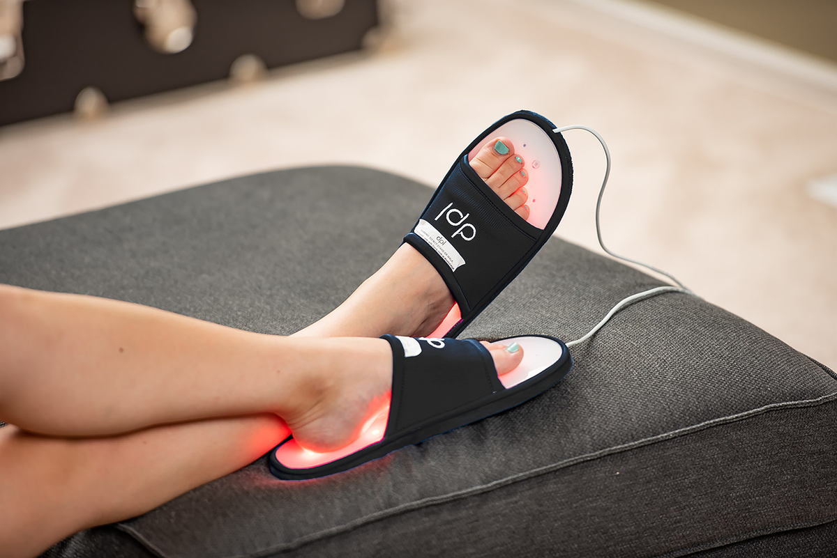 Feet wearing the DPL Red Light Therapy Slippers while on a couch