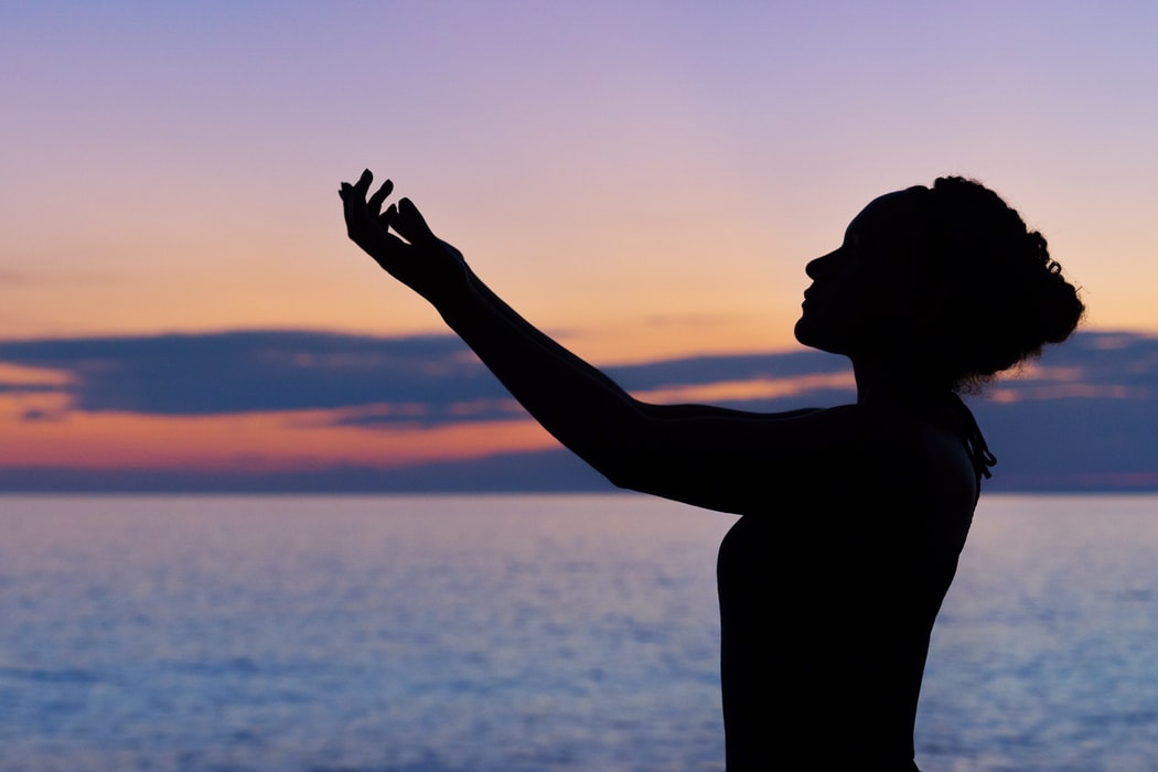 A woman in front of a sunset and water