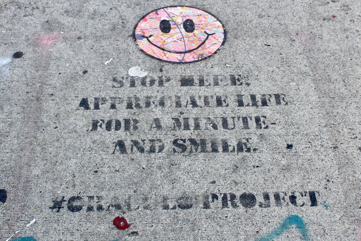 Concrete with graffitis that says “Stop here. Appreciate life for a minute and smile”