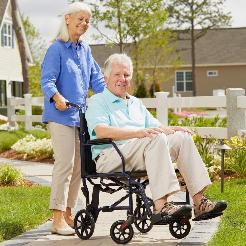 A woman pushing a man in a transfer chair